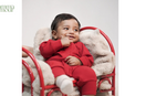 Baby in cherry red organic cotton romper sitting on a red and white chair - Mamma & Amour