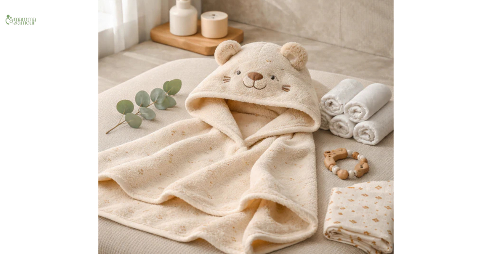 Beige organic cotton hooded baby bath towel with bear ears, folded beside candles and eucalyptus leaves - Mamma & Amour