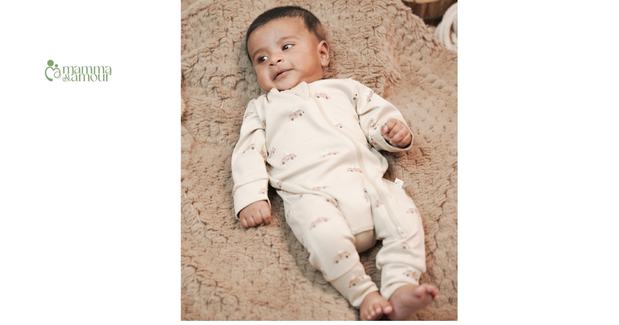 Baby boy wearing organic cotton sleepsuit lying on a soft blanket