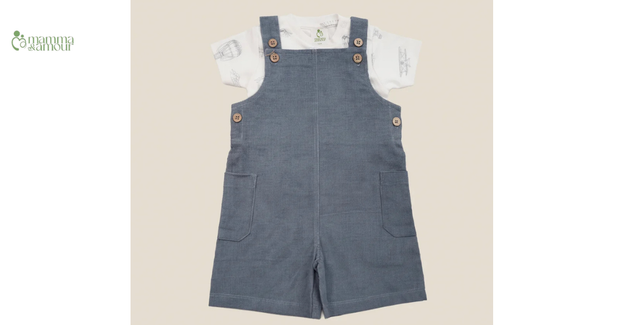 Mamma & Amour baby boy wearing organic cotton dungaree set sitting with a toy camera