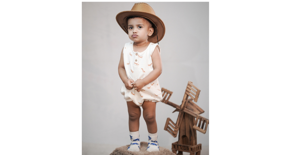 Here's the alt text for this image: Alt Text Baby boy in cotton romper standing outdoors - cotton baby rompers online India