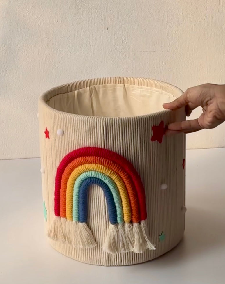 Handwoven macrame nursery storage basket featuring a colorful rainbow and stars for kids room decor.
