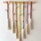 Classic macrame memory wall photo hanger with colorful cords and wooden clips for nursery decor