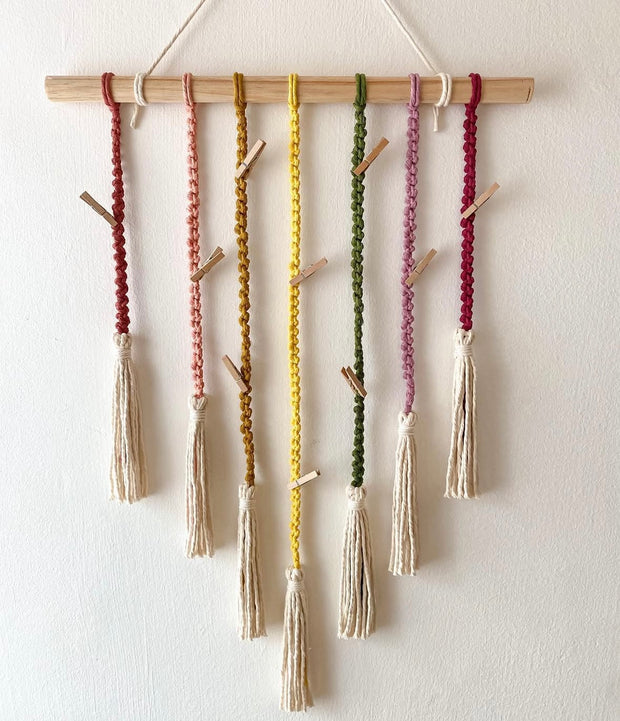 Classic macrame memory wall photo hanger with colorful cords and wooden clips for nursery decor