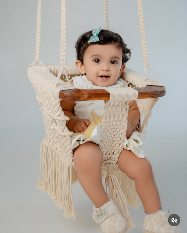 Baby sitting in Mamma & Amour handcrafted macrame and wood baby swing in nursery